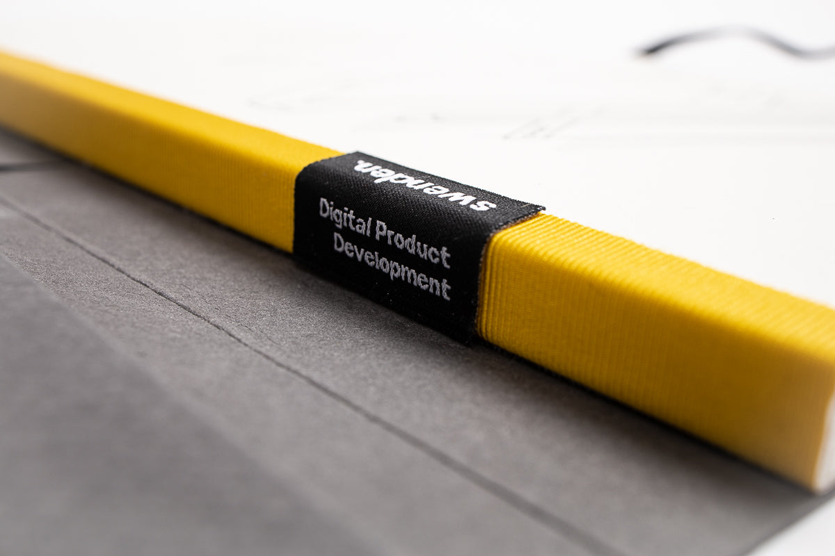 Detailaufnahme von einem individuellen Notizbuch mit einem personalisierten Etikett am Bund. Das Etikett wurde für den Kunden speziell gewebt. Hergestellt von Tyyp in Deutschland.