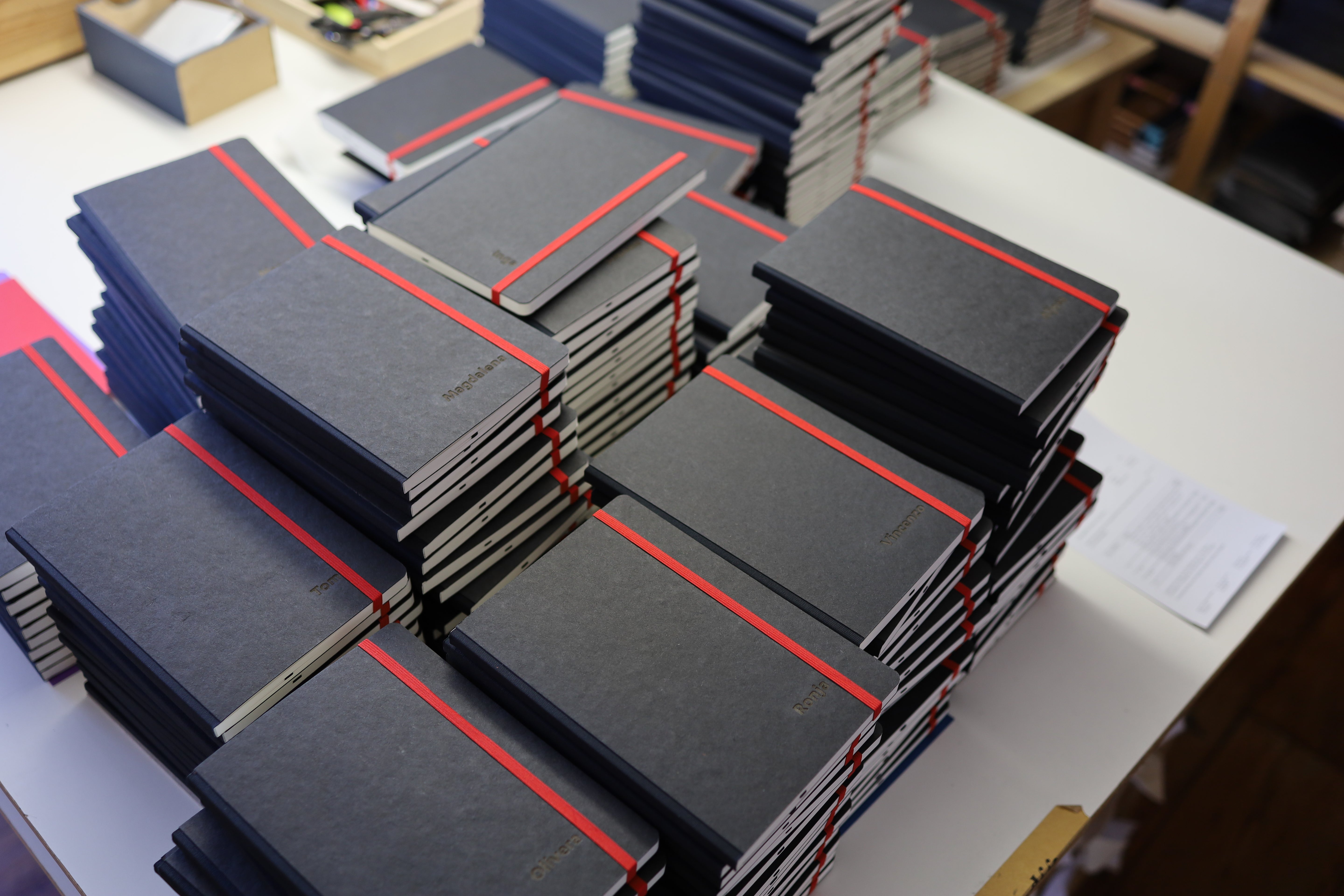 Notizbuch mit einzelnamen lasergravur personalisiert mit CD Typo. Schwarz mit roten Gummiband nach Corporate Design des Kunden